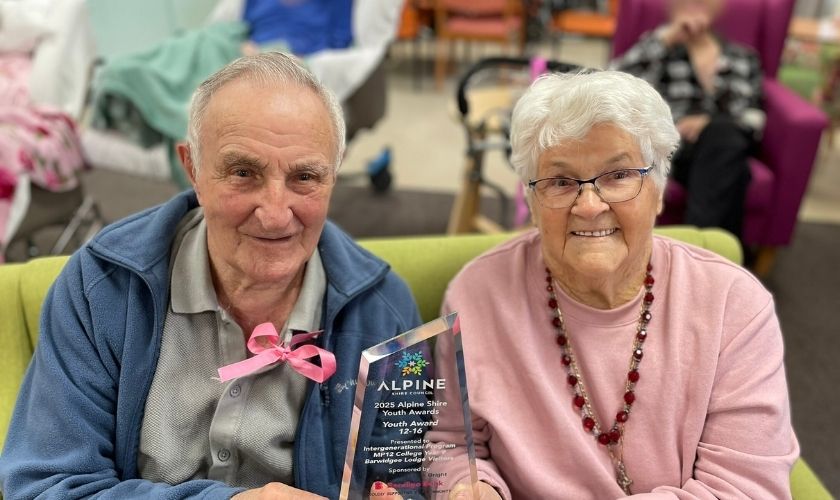 two older people holding an award