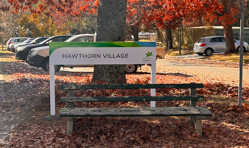 Hawthorn Village sign with autumn leaves in the background Hawthorn Village sign with autumn leaves in the background