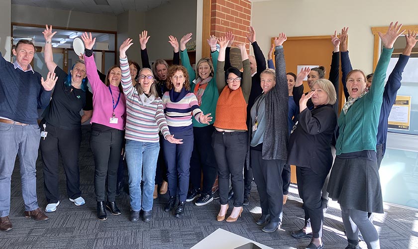 group of staff from the community care smiling with their hands in the air